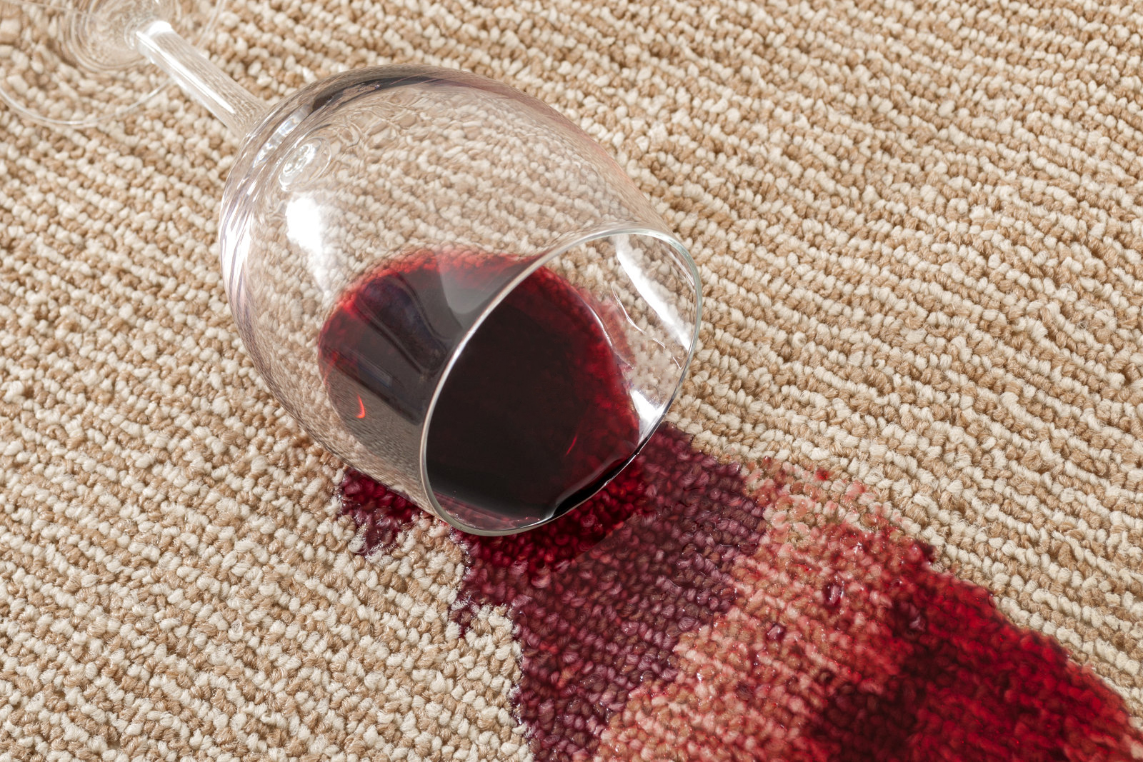 Концепт кућне несреће и кућне несреће са крупним планом проливене чаше црног вина на смеђем тепиху